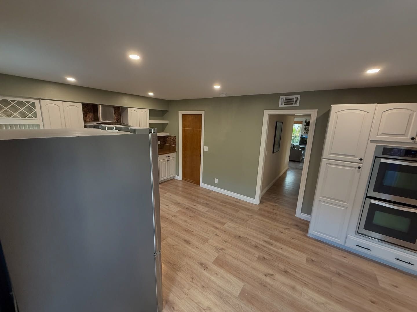 Kitchen interior with white cabinets, stainless steel appliances, and wood flooring.