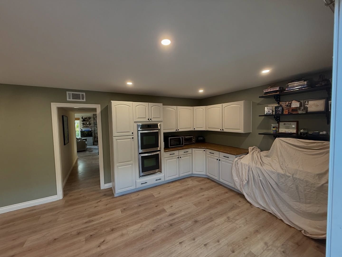 Kitchen with white cabinets, wooden countertops, and light brown flooring.