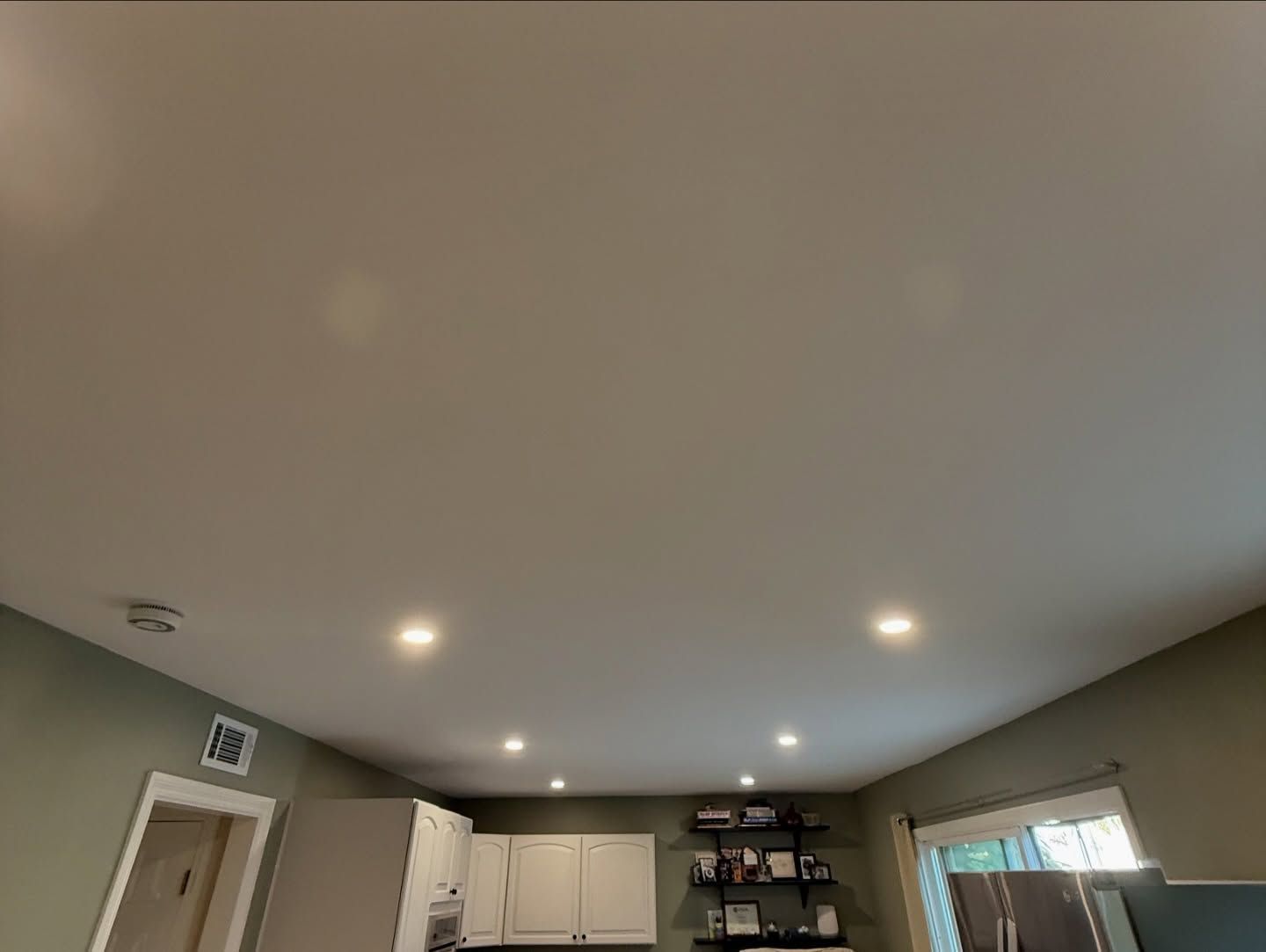 Ceiling with recessed lights in a kitchen. Cabinets and open shelves below.