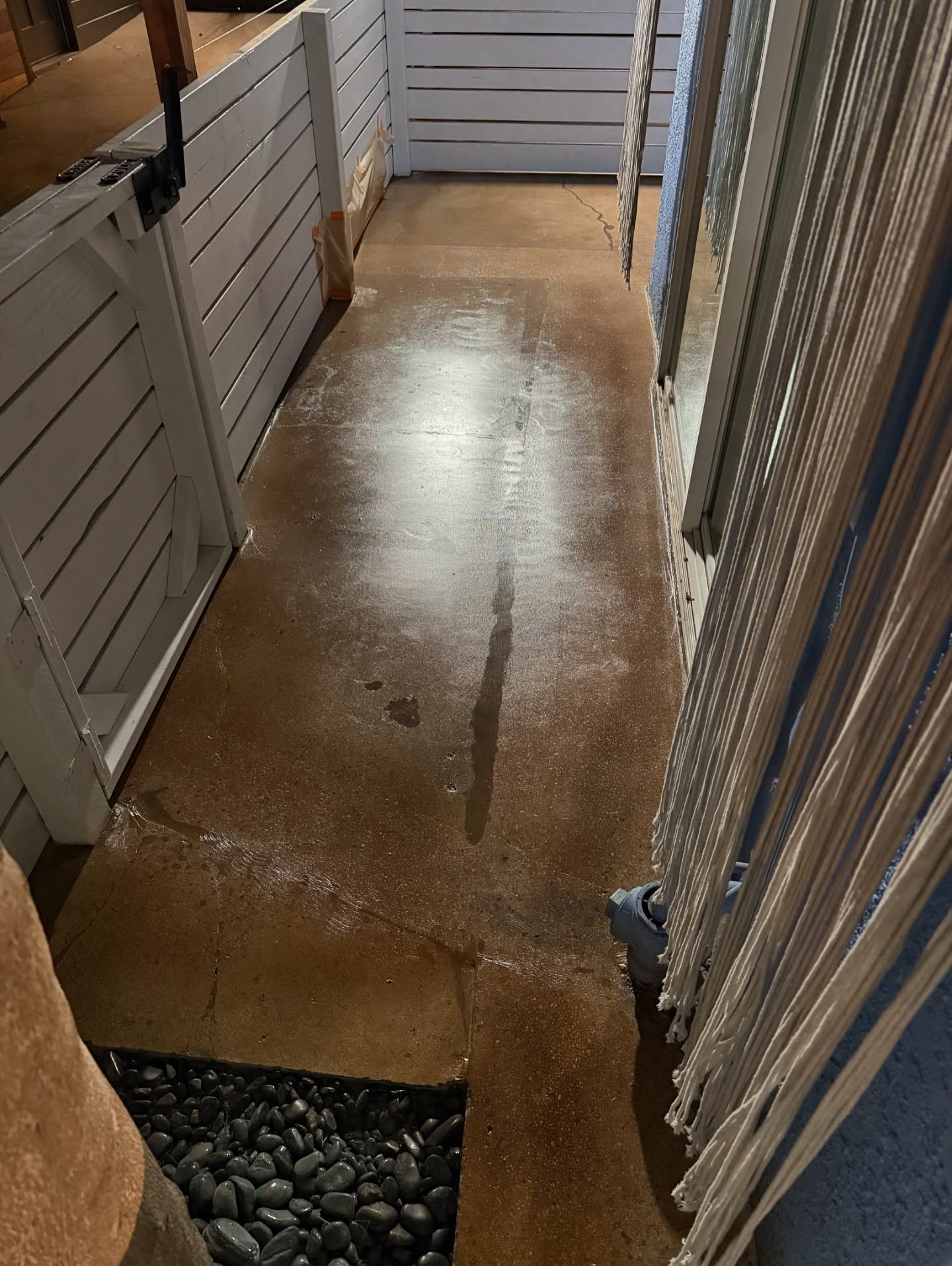 Concrete pathway with white fence and beaded curtain. Spot with apparent water stain.
