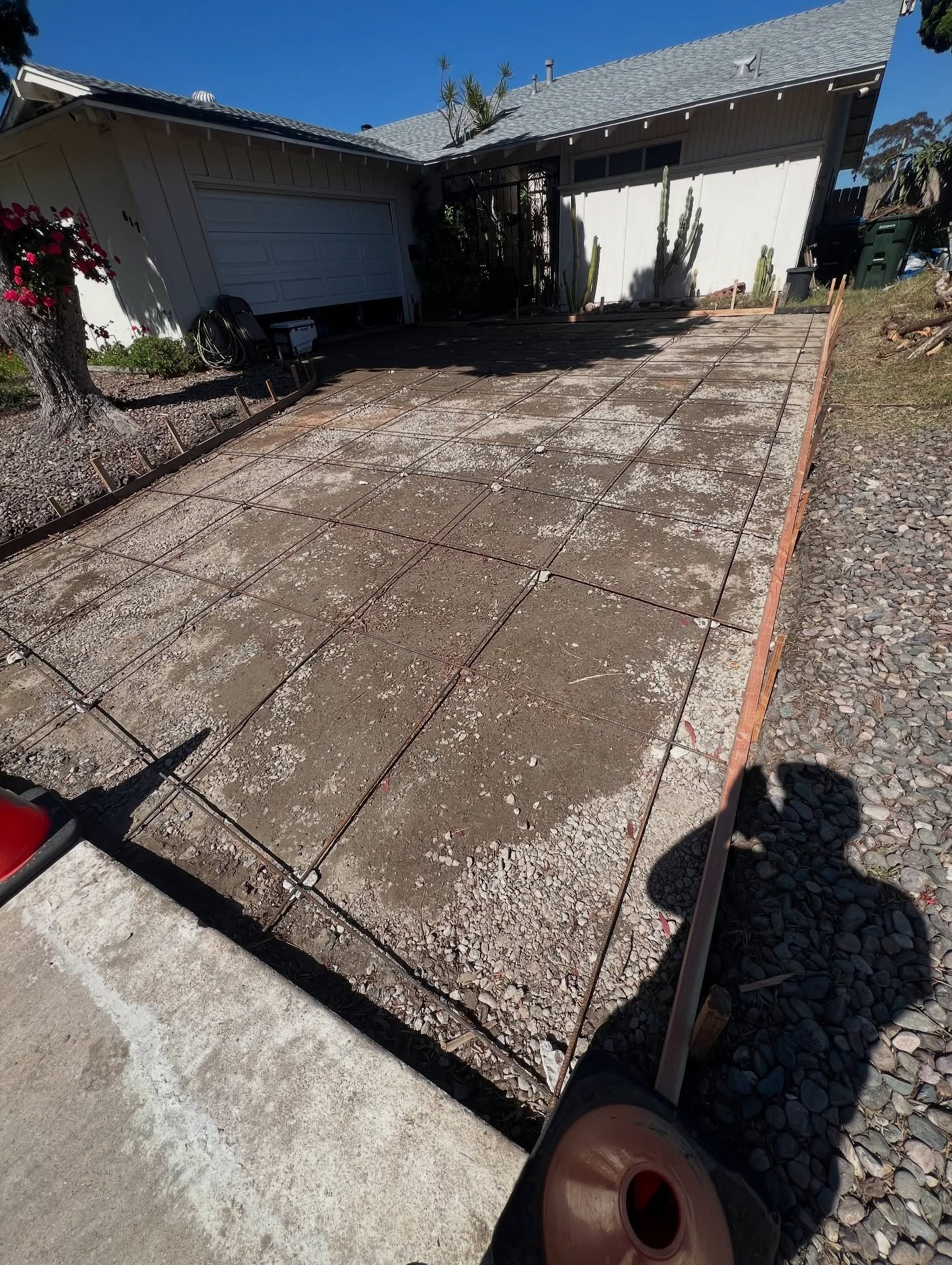 Driveway concrete surface partially deteriorated, next to a home with garage.