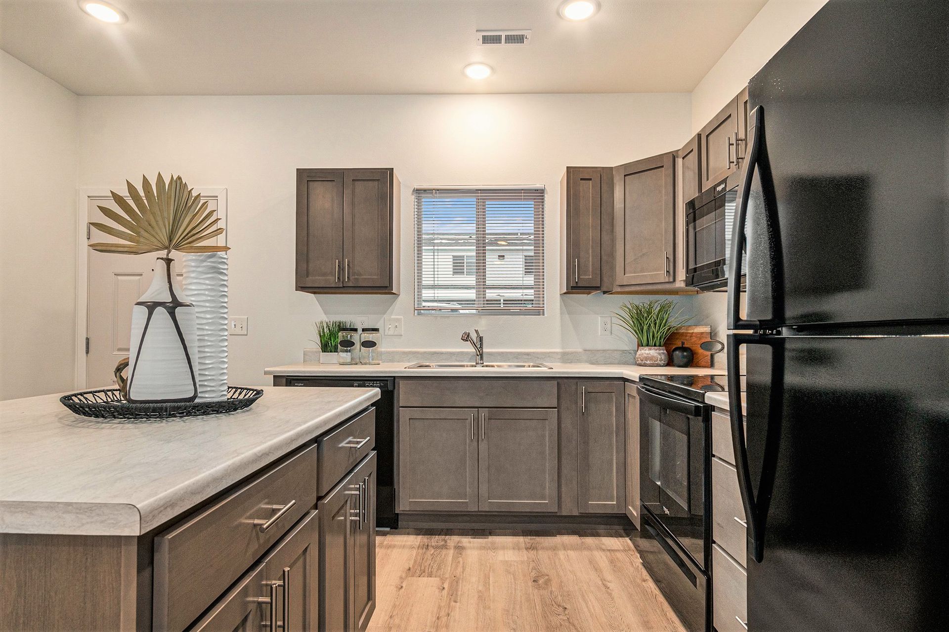 A kitchen with a black refrigerator , stove , and microwave.