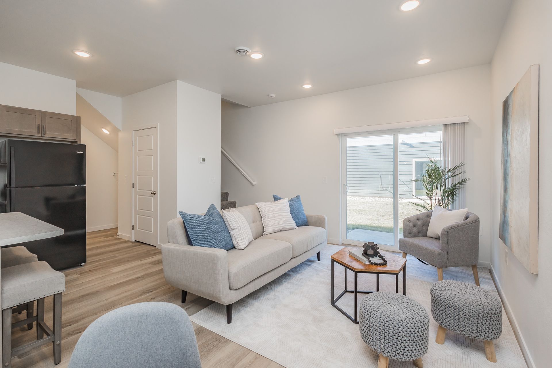 A living room with a couch , table , chairs and stairs leading to the kitchen.