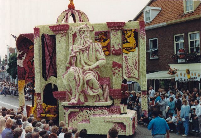Een standbeeld van een man staat op een praalwagen in een parade