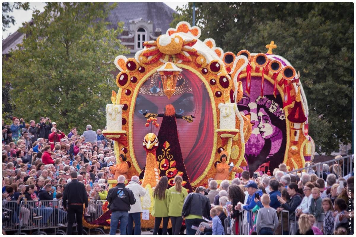 Een groep mensen kijkt naar een optocht met een praalwagen die op een spiegel lijkt.