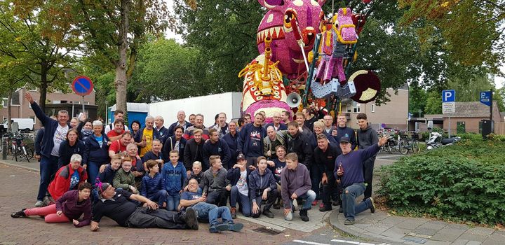 Een groep mensen poseert voor een foto voor een groot standbeeld.