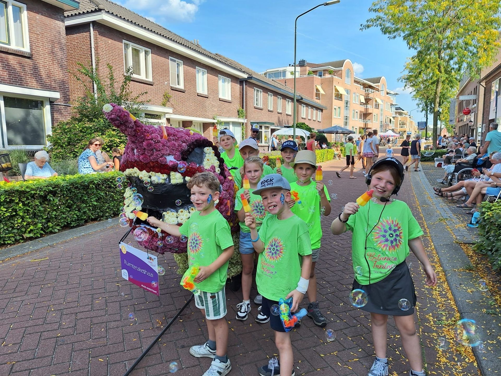 Een groep kinderen loopt in een optocht door een straat.
