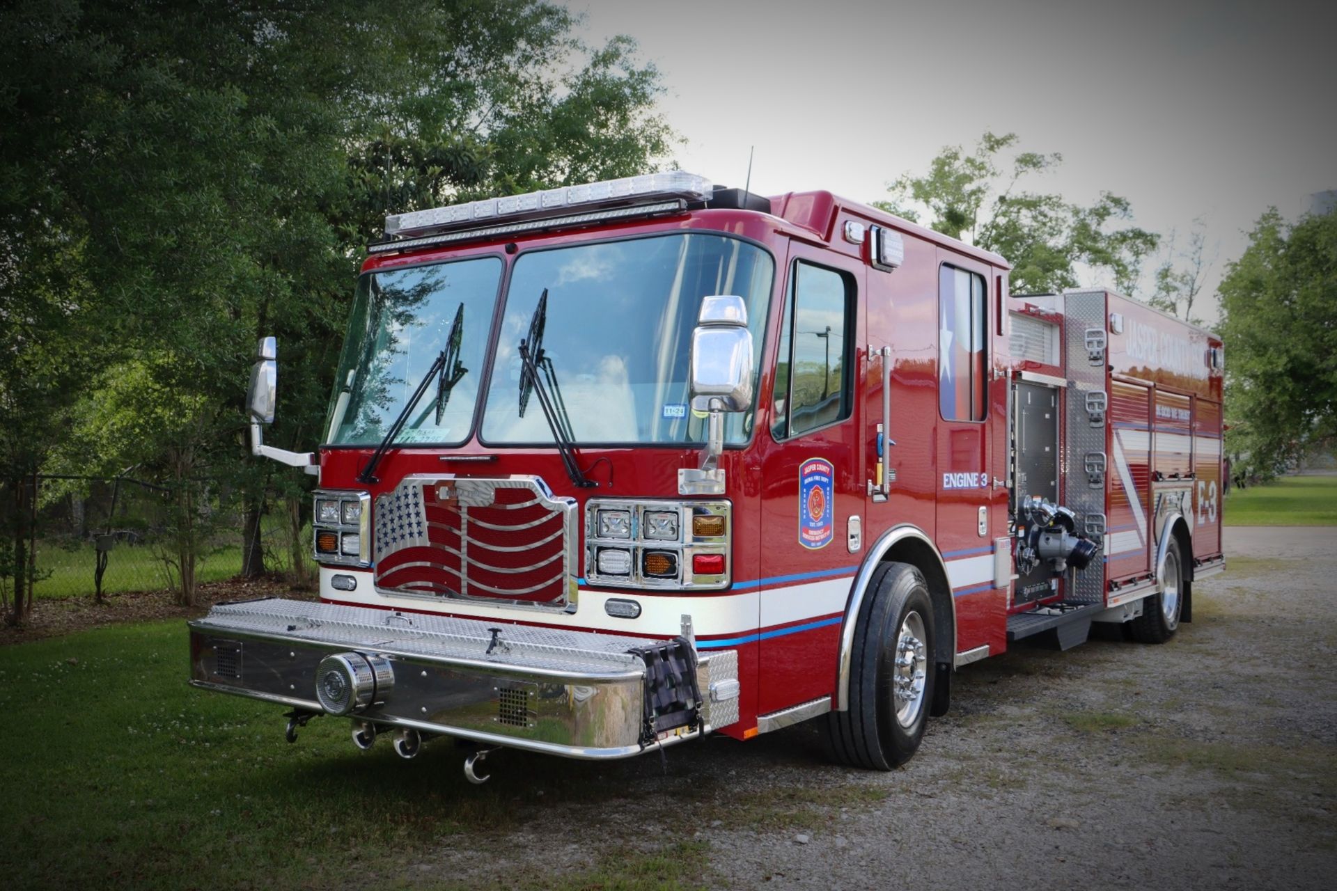 A red fire truck is parked in a gravel lot
