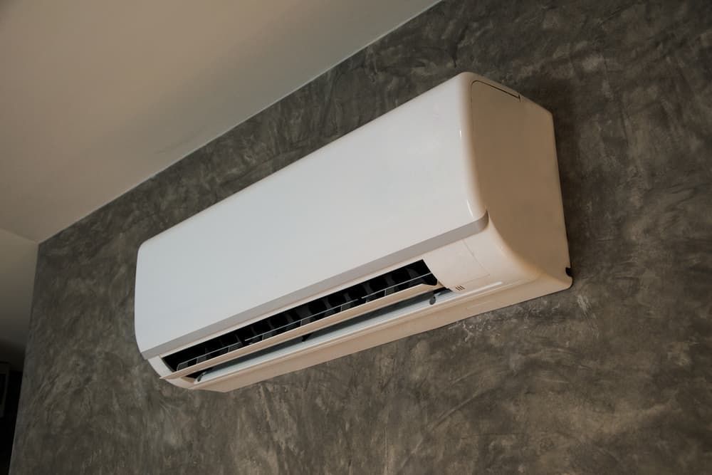 Air conditioning unit mounted on a tan wall above a window. A white doorway is visible on the right.