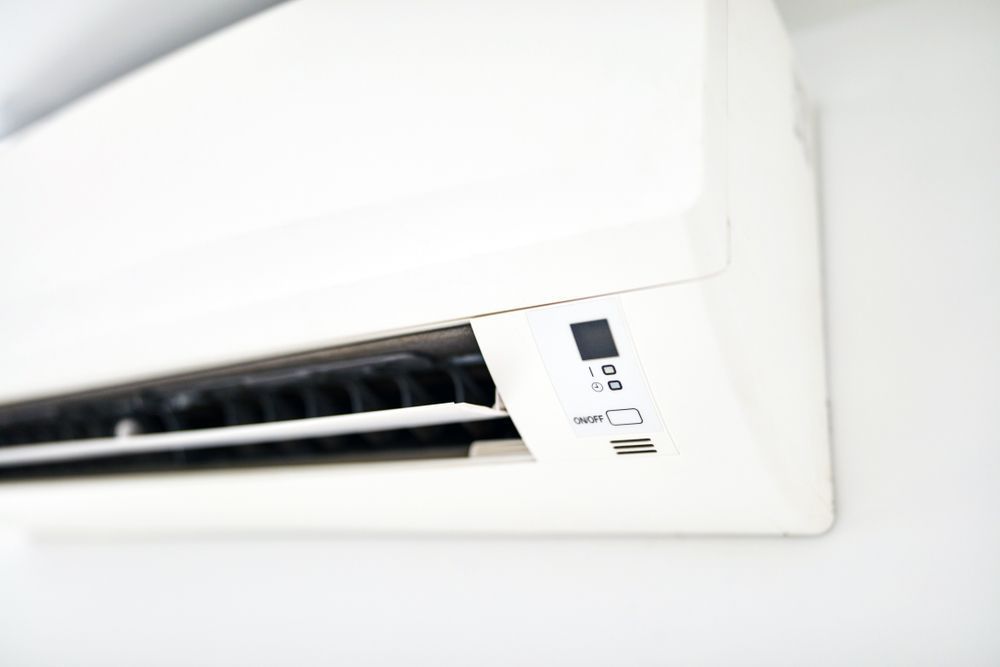 White wall-mounted air conditioner with vents open, controls visible.
