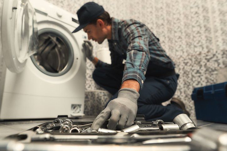 Choosing the right tool. Plumber repairing washing machine