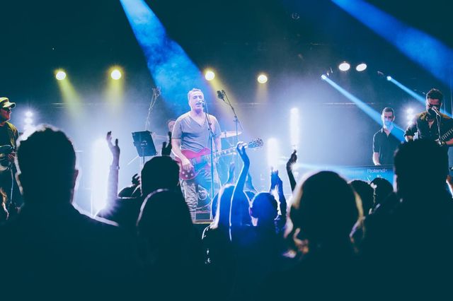 A man is playing a guitar on stage in front of a crowd of people.