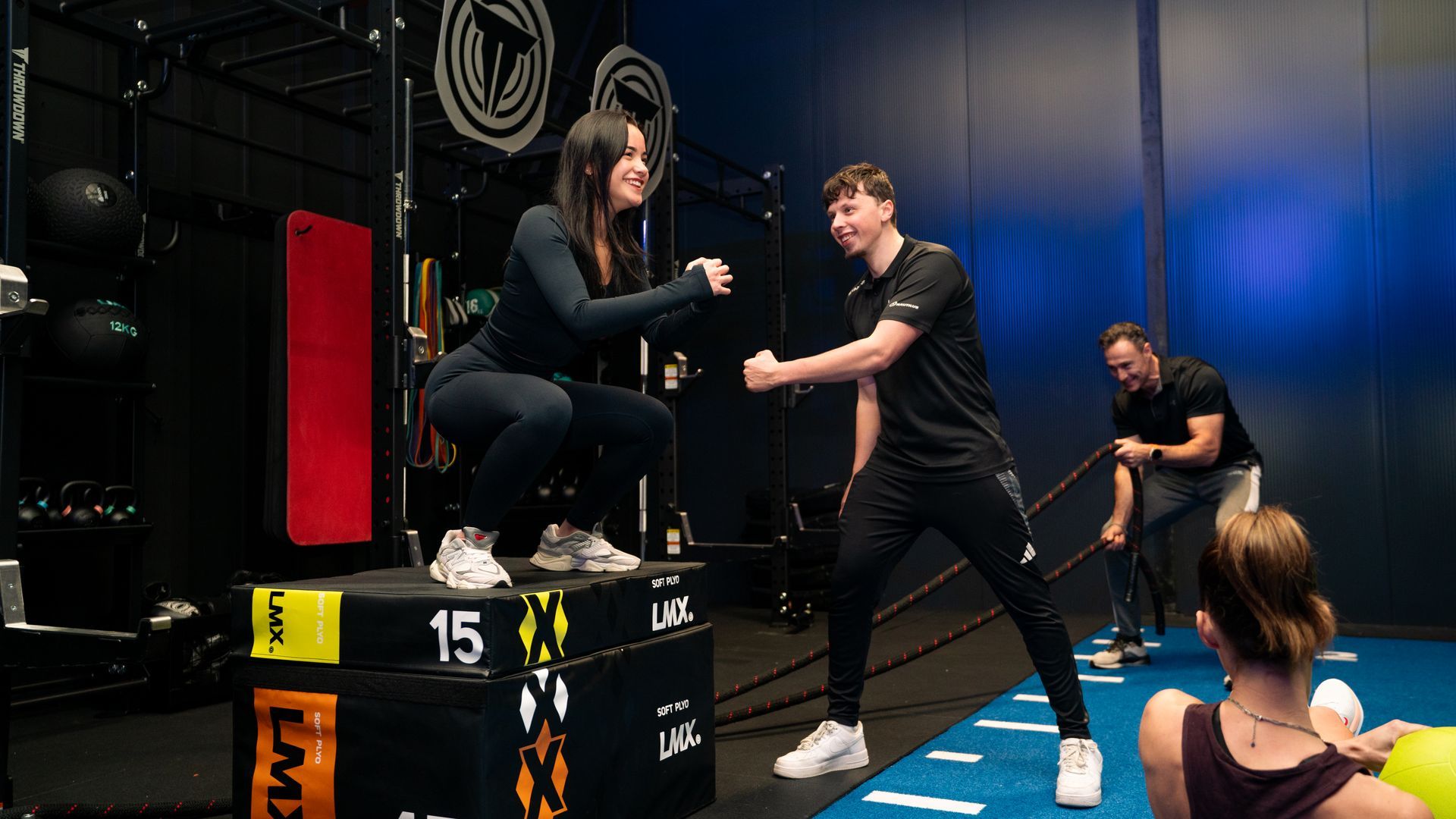 Interieur van een sportschool met loopbanden, halterbanken en gewichten bij de ramen.