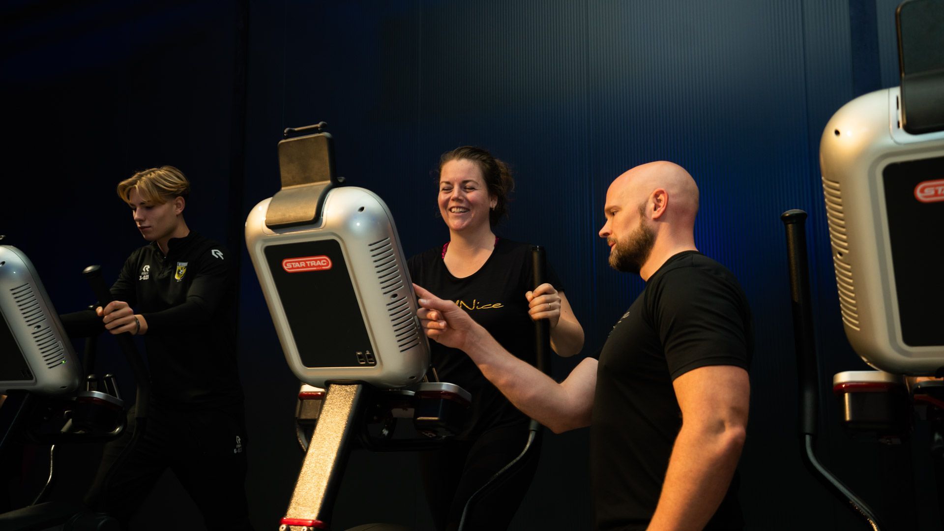 Vrouw in een wit shirt doet een triceps-oefening met een halter in de sportschool.