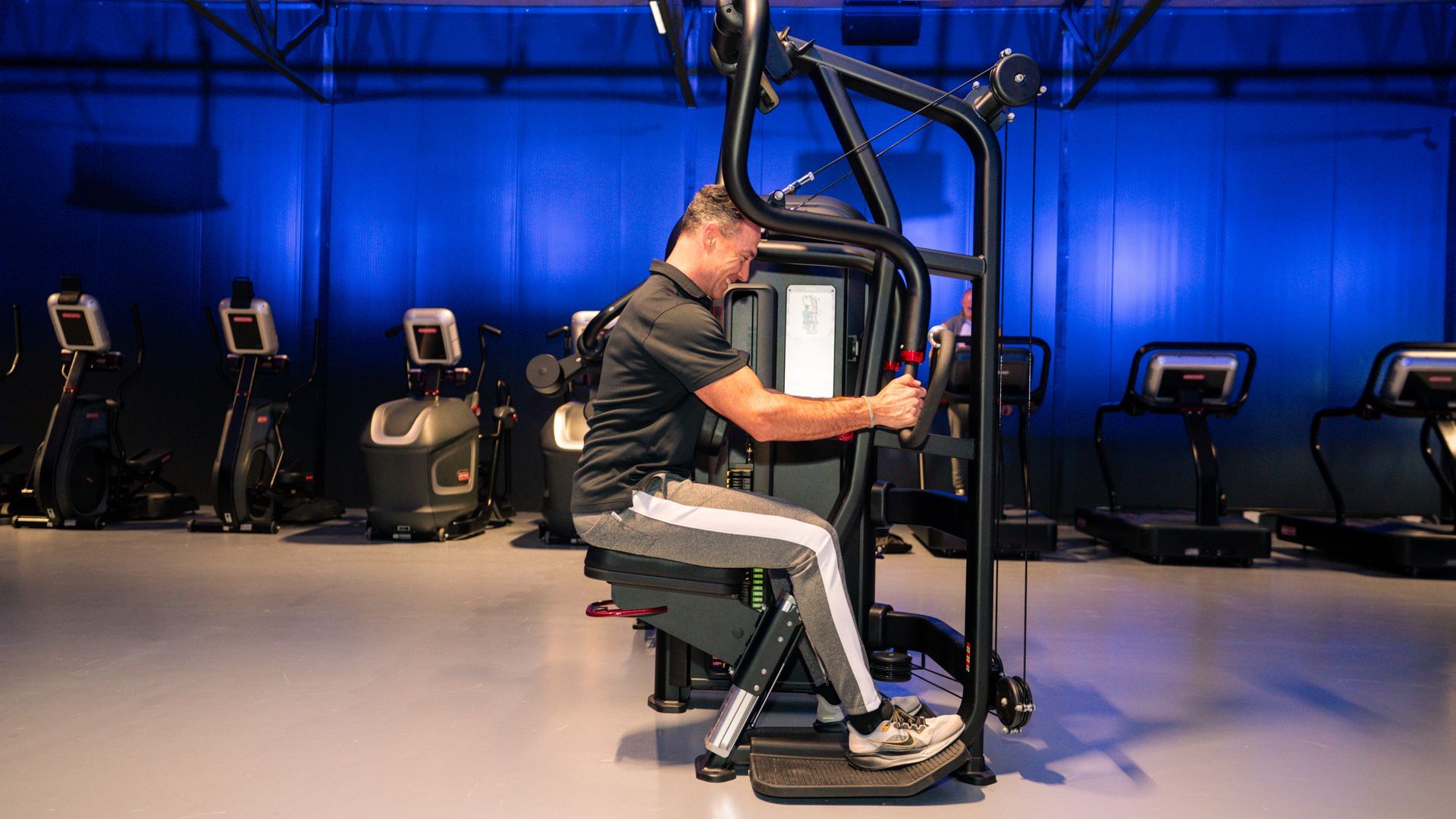 Vrouw in een wit shirt doet een triceps-oefening met een halter in de sportschool.