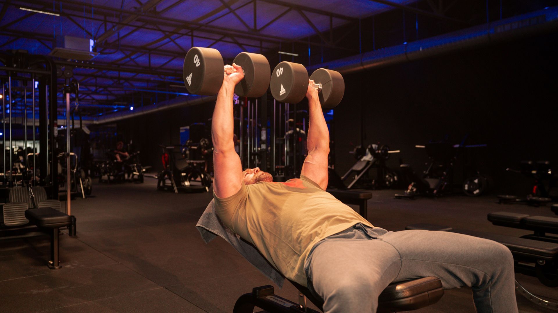 Mensen trainen met weerstandsbanden in een sportschool. Armen omhoog, geconcentreerde gezichtsuitdrukkingen.