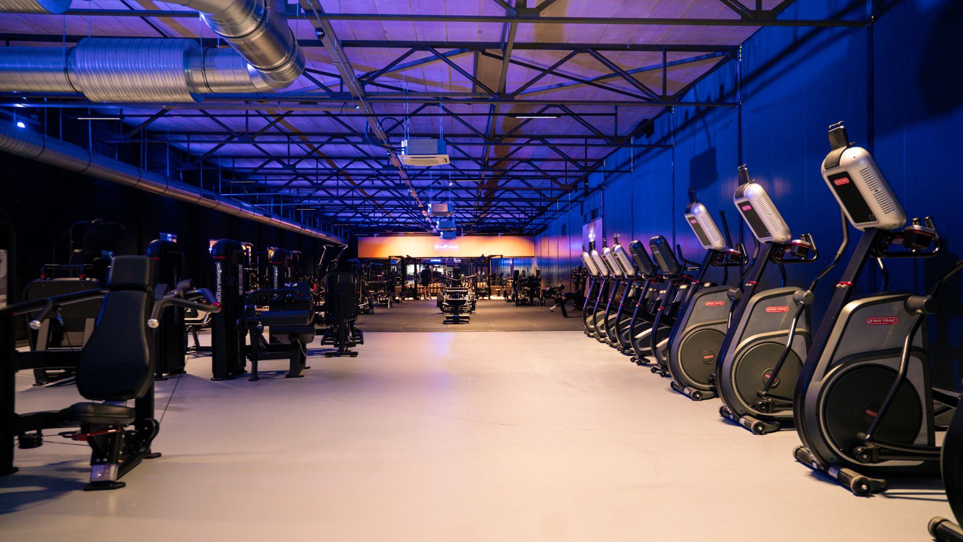 Gewichthefschijven in de kleuren rood, blauw, geel, groen en beige, met een halter op de vloer van een sportschool.