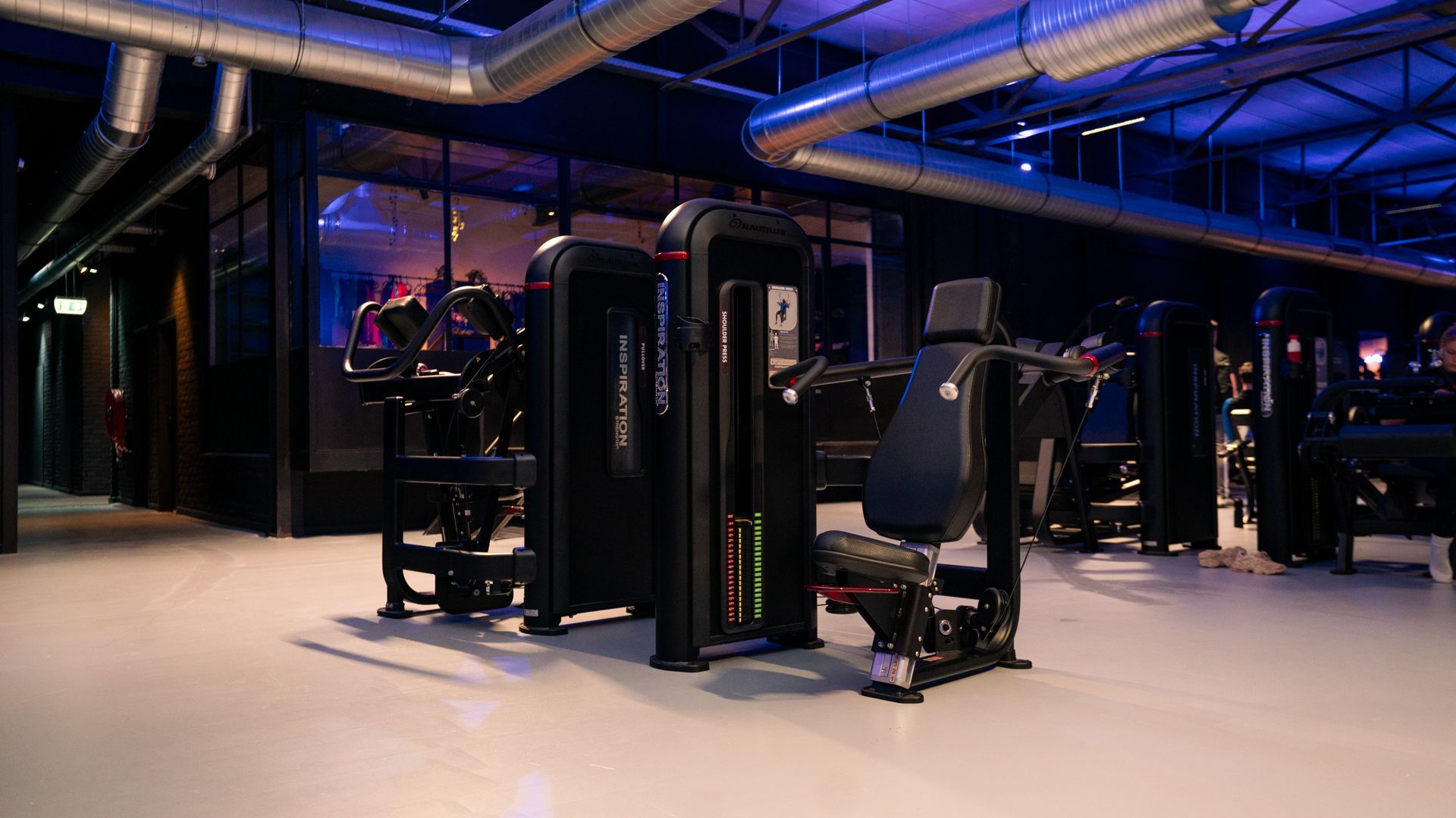 Rijen zwarte halters op een rek in een sportschool, tegen een onscherpe achtergrond.