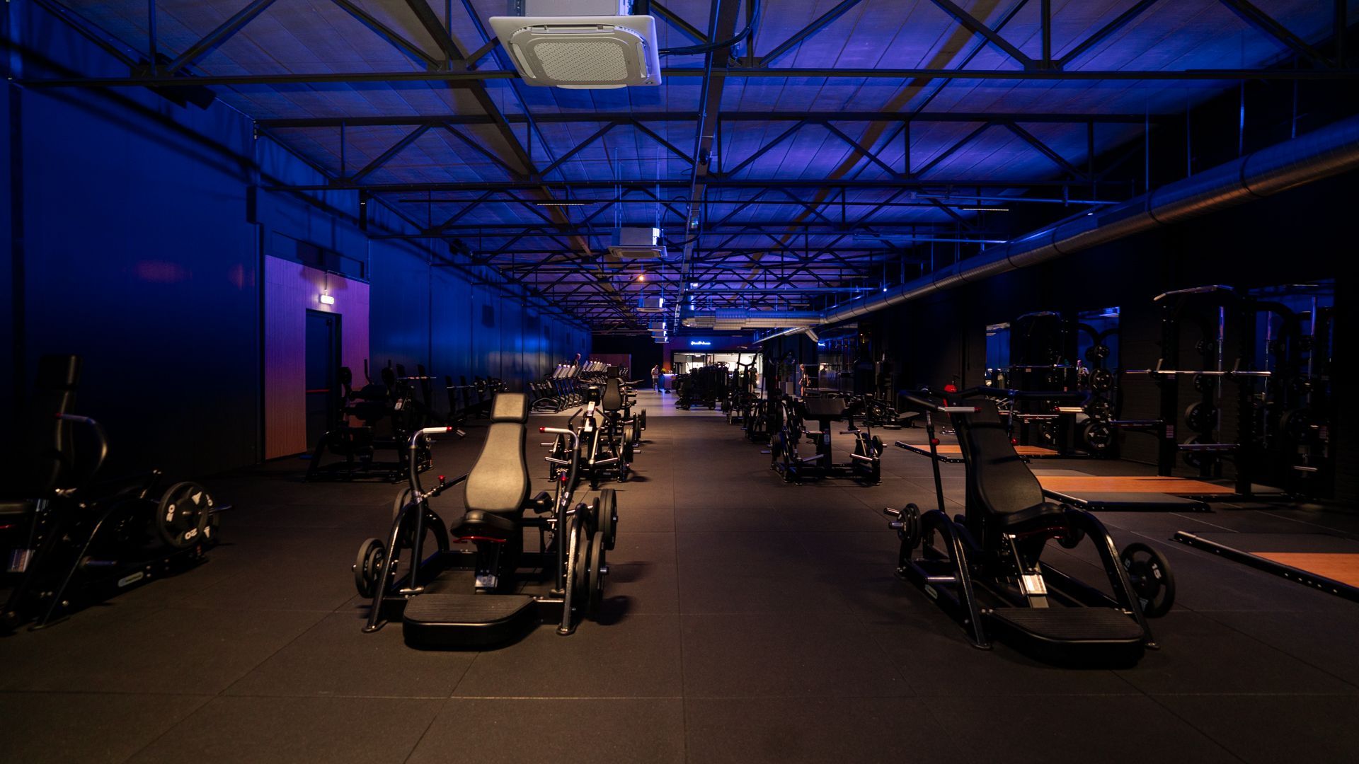 Rijen zwarte halters op een rek in een sportschool, tegen een onscherpe achtergrond.