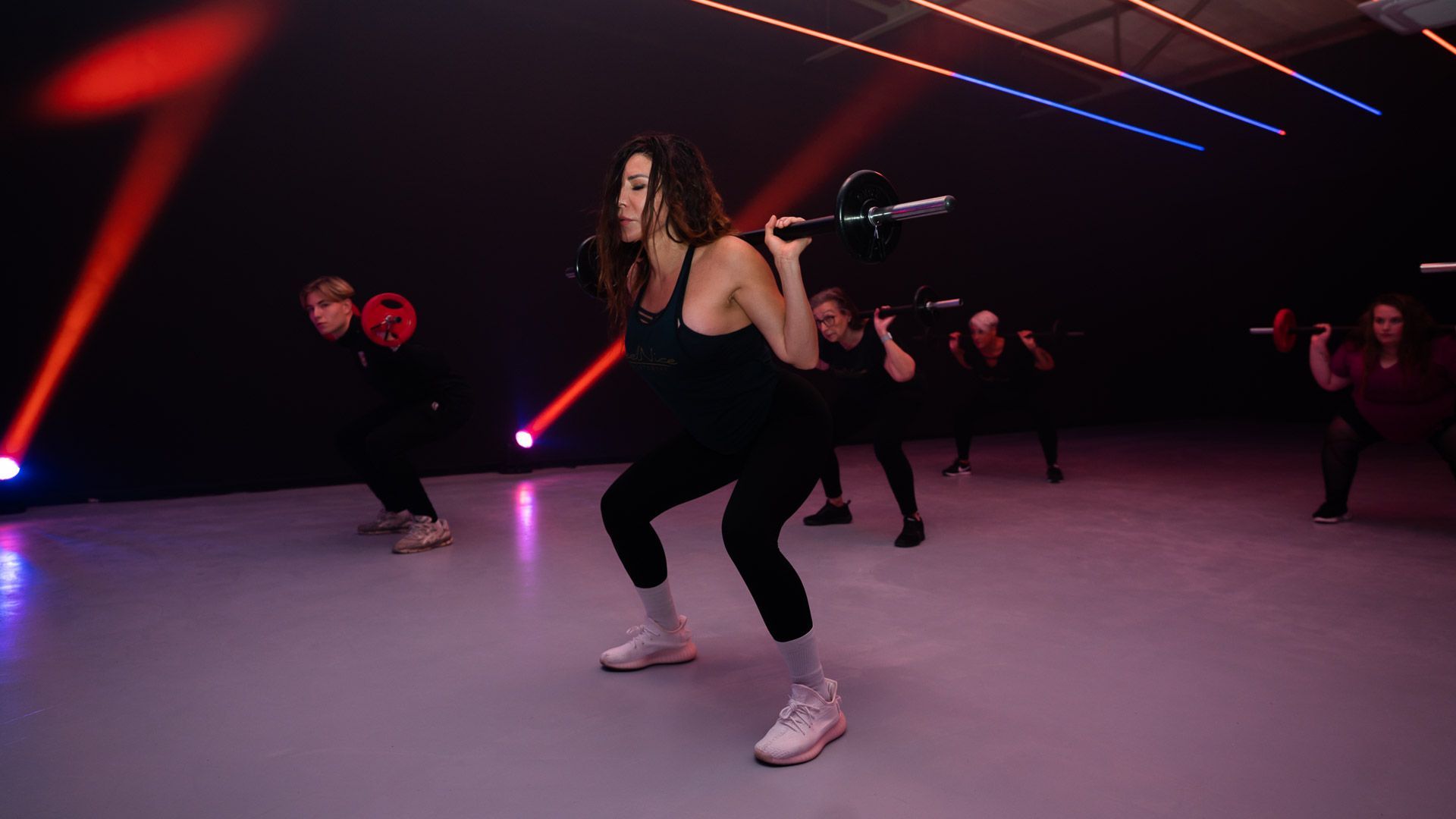 Mensen beoefenen buiten yoga, waarbij ze zich uitrekken op matten; oranje shirt.