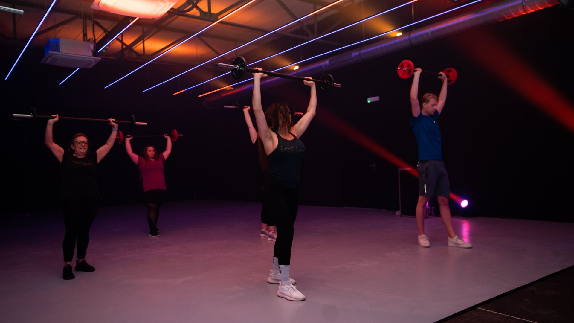Gewichthefschijven in de kleuren rood, blauw, geel, groen en beige, met een halter op de vloer van een sportschool.