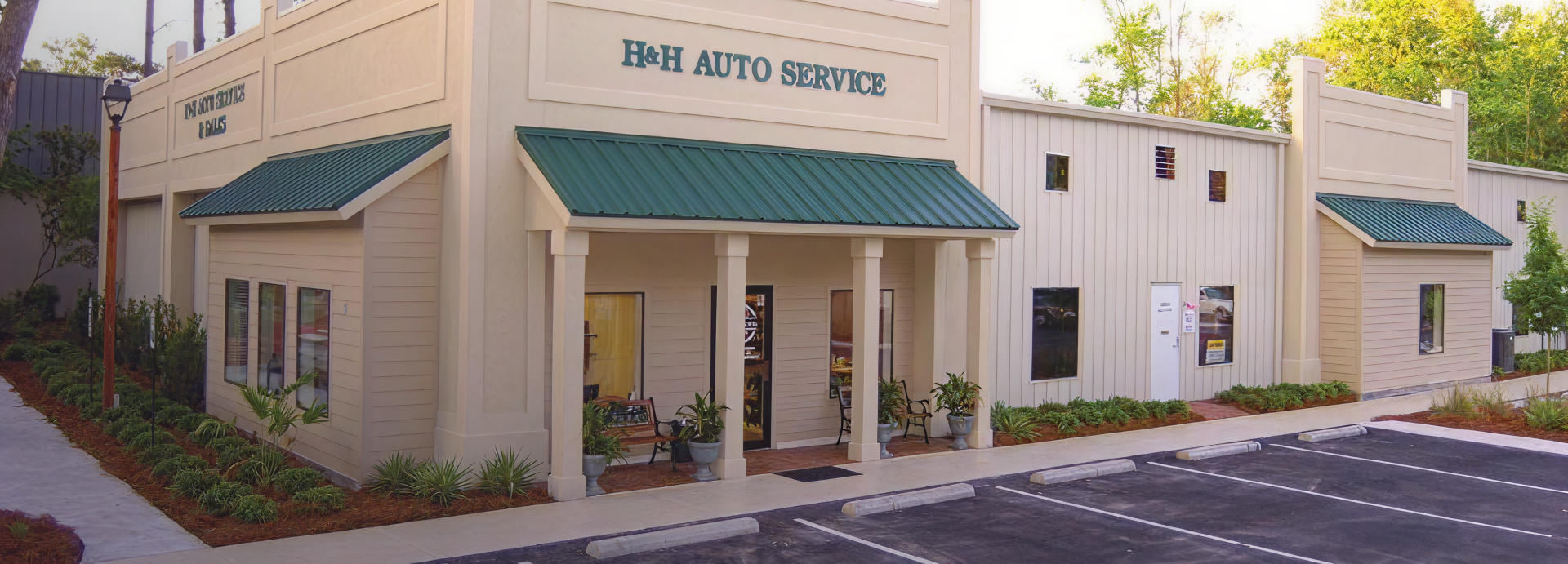 Small beige building with green awnings and the sign “B&H AUTO SERVICE” above the entrance.