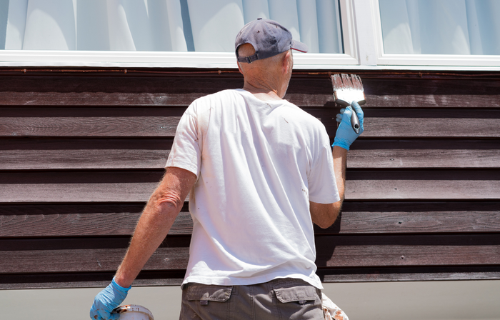 Painting the siding of a house in EL Paso.