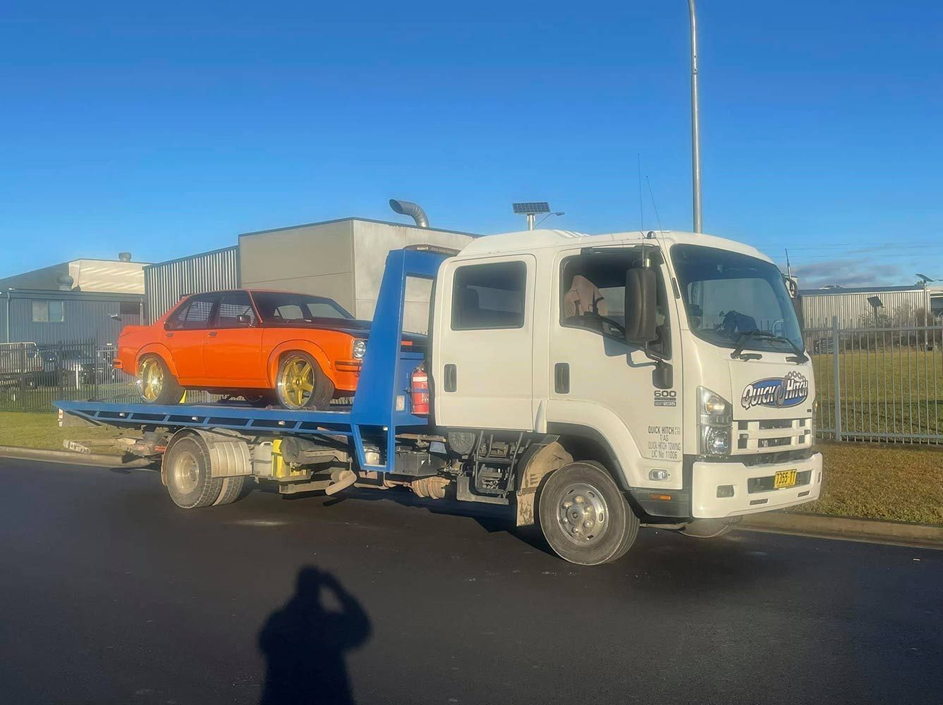 A Tow Truck is Carrying a Car on the Back of It — Quick Hitch Towing & Tilt Tray Services Illawarra in Oak Flats, NSW