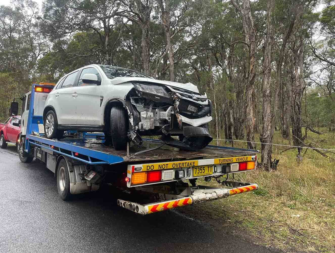 A White Car is Being Towed by a Tow Truck — Quick Hitch Towing & Tilt Tray Services Illawarra in Oak Flats, NSW
