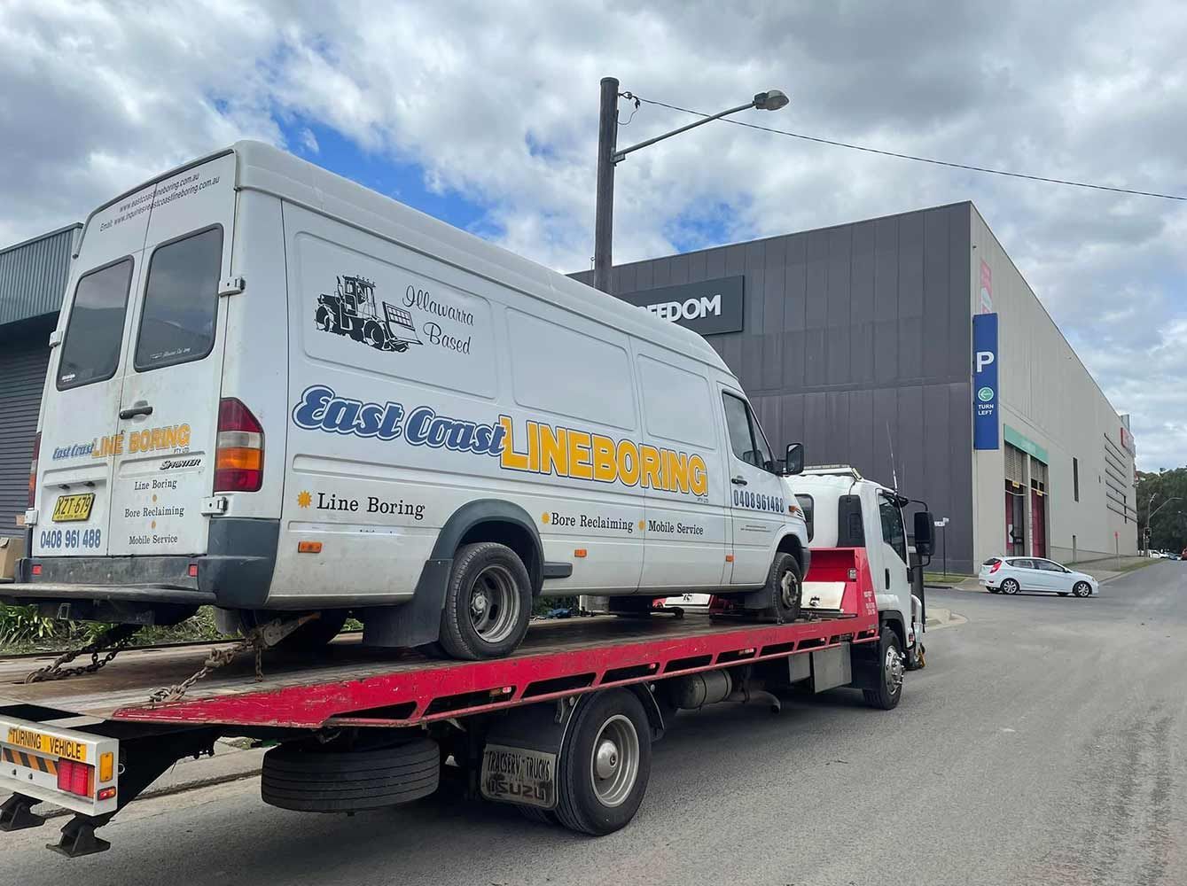 A White Van is Sitting on Top of a Red Tow Truck — Quick Hitch Towing & Tilt Tray Services Illawarra in Oak Flats, NSW