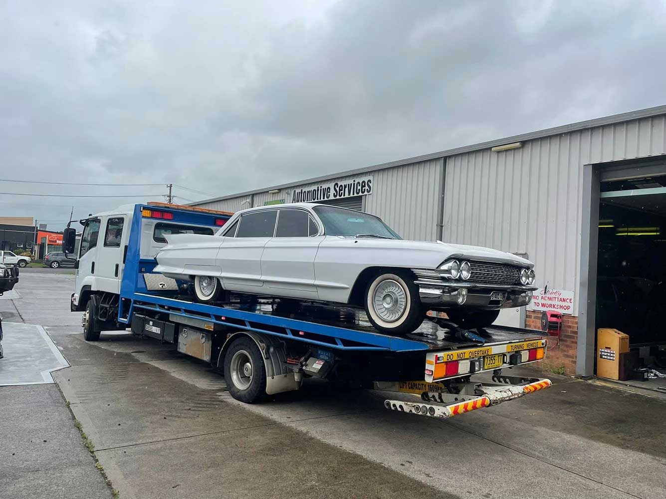 A White Car is Being Towed by a Tow Truck — Quick Hitch Towing & Tilt Tray Services Illawarra in Oak Flats, NSW