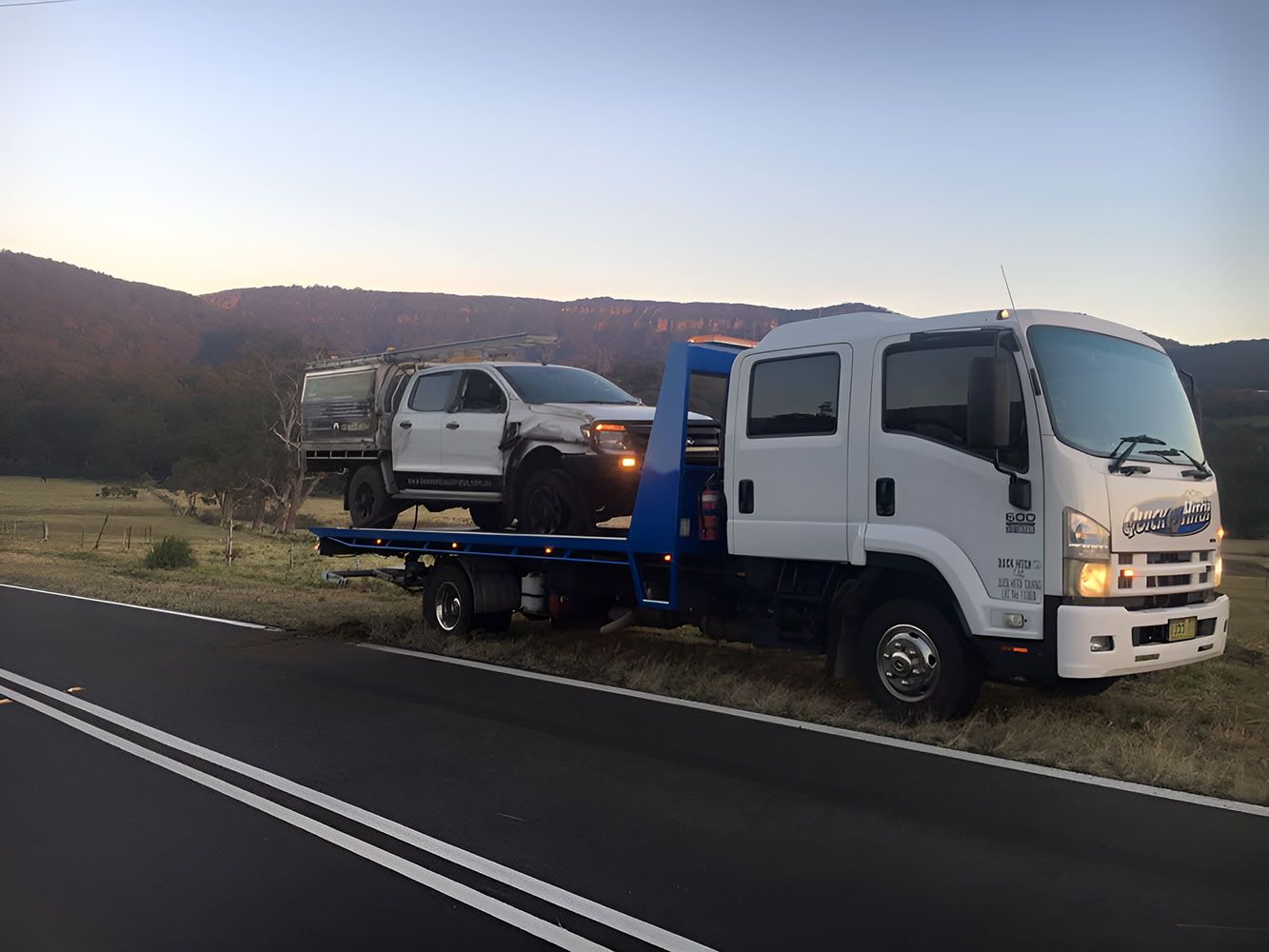 A Tow Truck is Towing a Car on the Side of the Road — Quick Hitch Towing & Tilt Tray Services Illawarra in Shellharbour, NSW