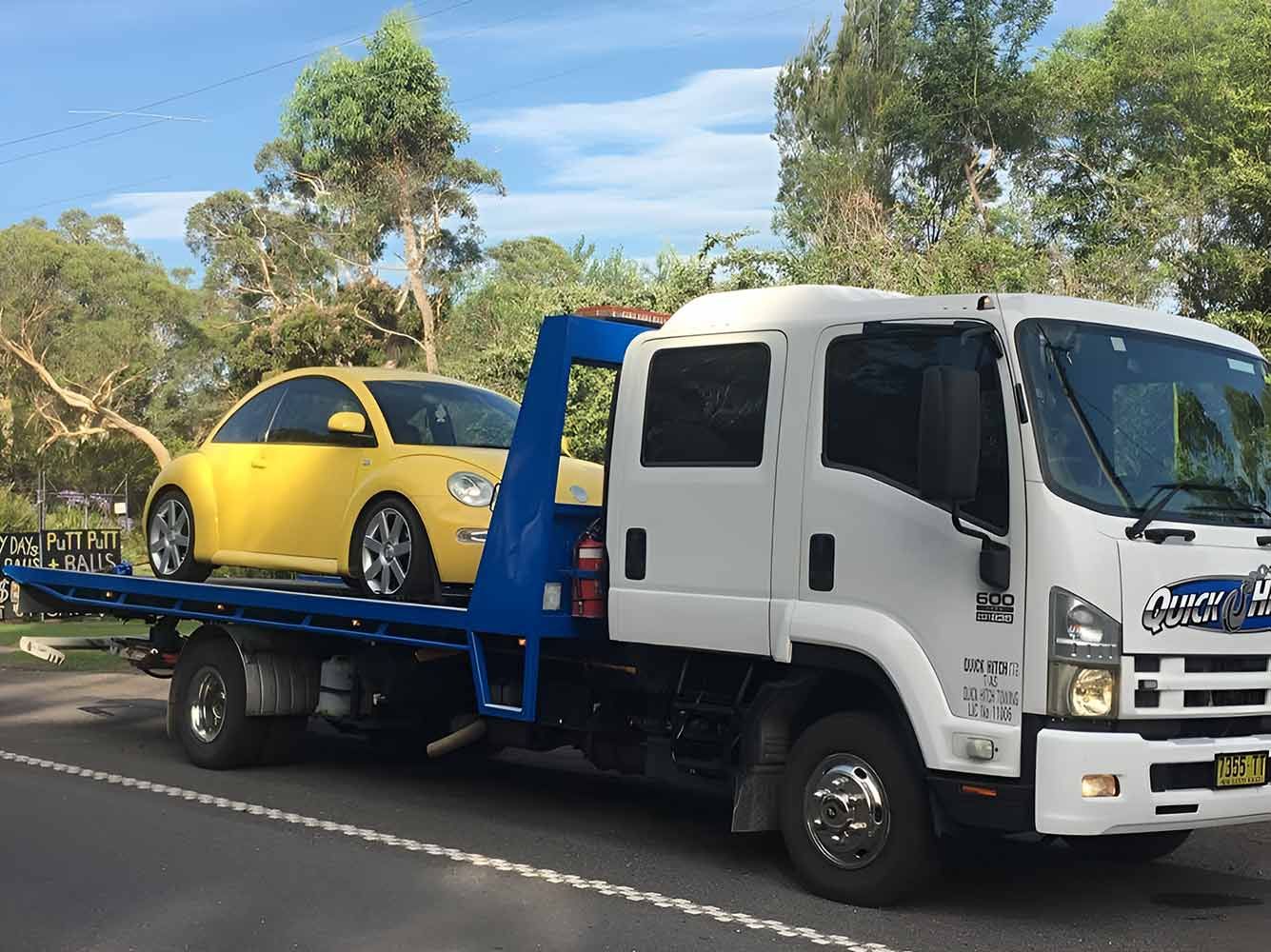 A Tow Truck With a Car on the Back is Parked Roadside — Quick Hitch Towing & Tilt Tray Services Illawarra in Oak Flats, NSW