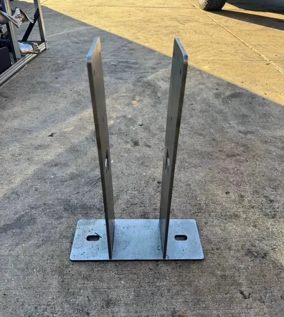 Two workers in a bright industrial workshop: one grinds metal, creating sparks, while the other performs welding nearby.