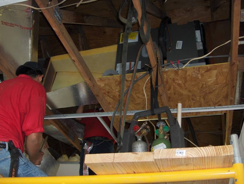 A man in a red shirt is working on a ceiling