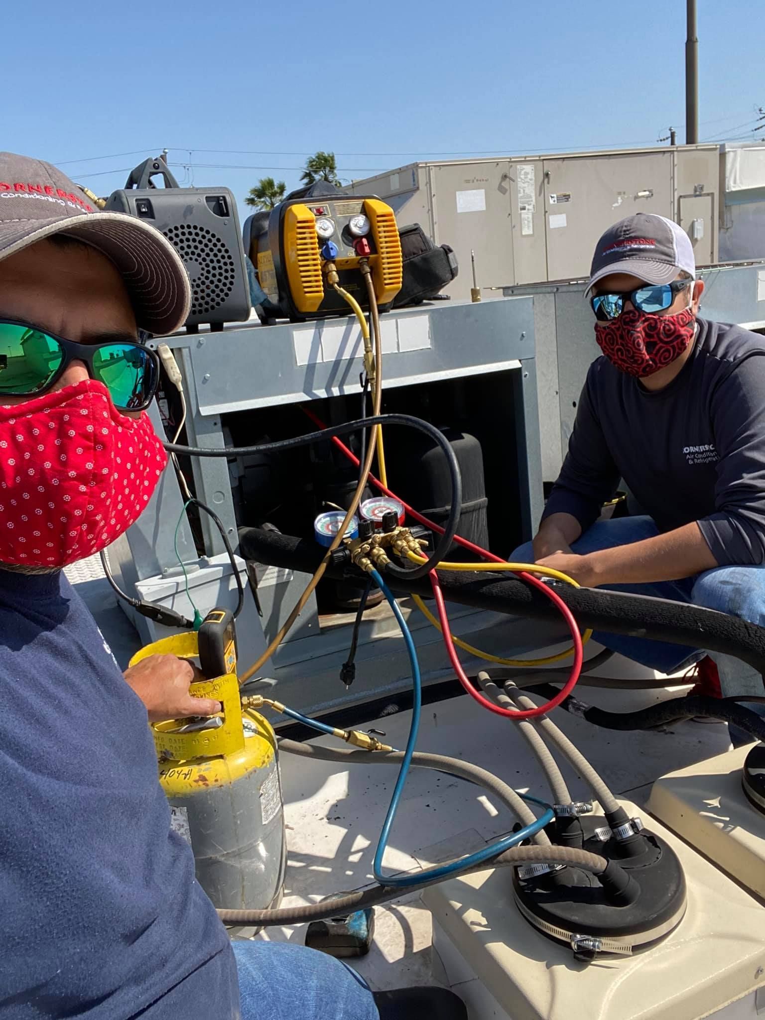 A man wearing a mask and sunglasses is working on a machine.