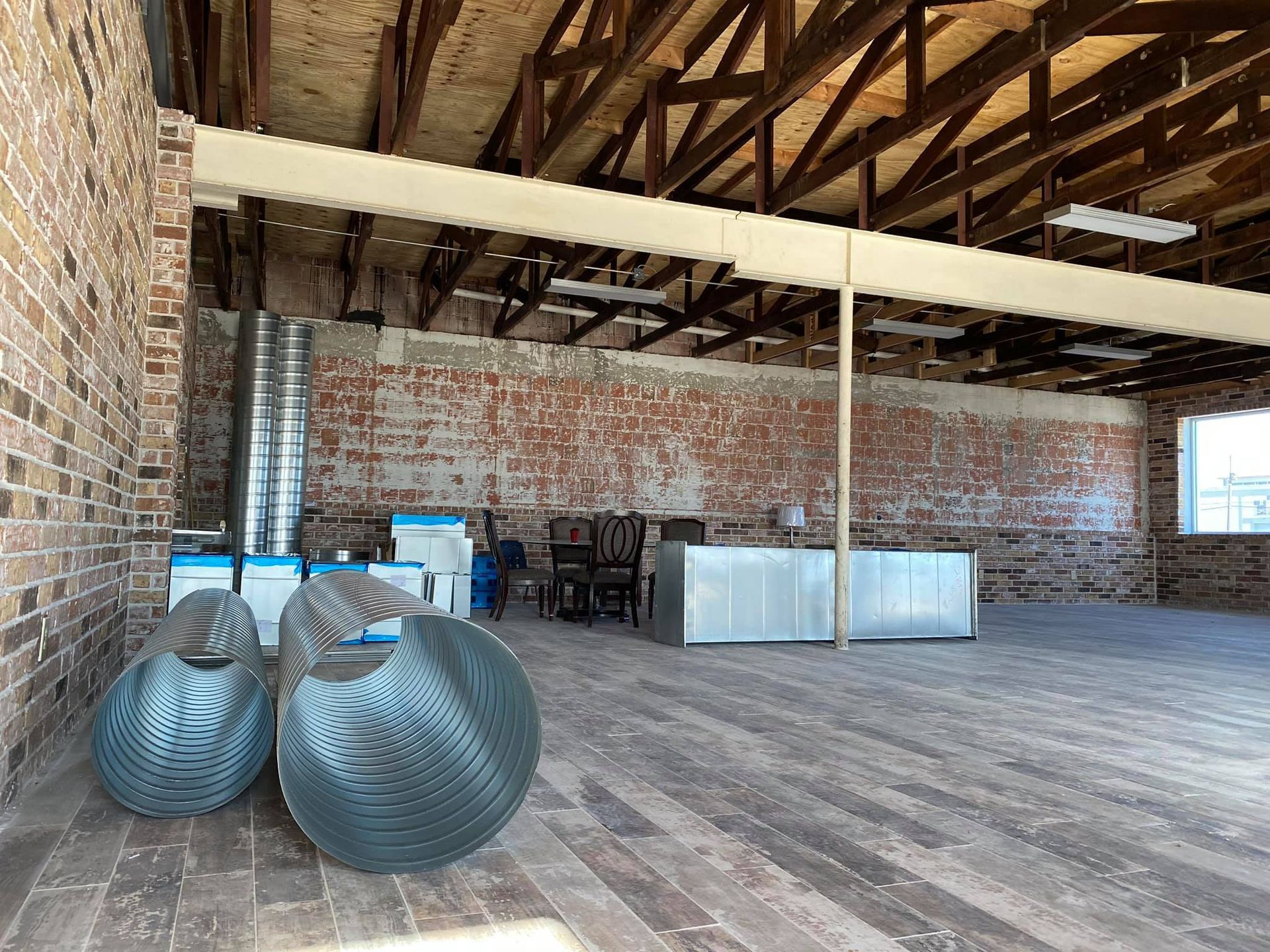 A large empty room with a brick wall and a wooden floor.