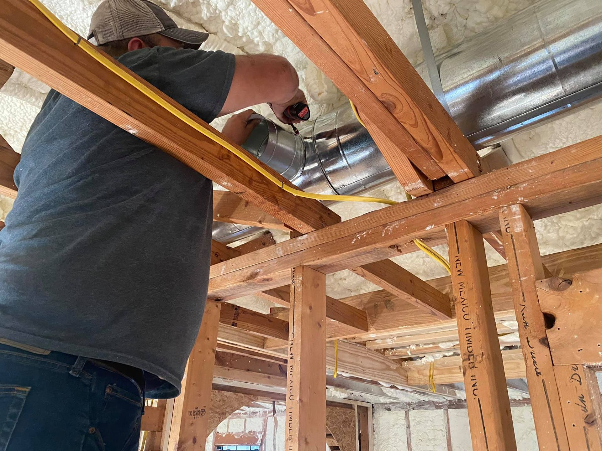 A man is measuring a pipe in the ceiling of a house.