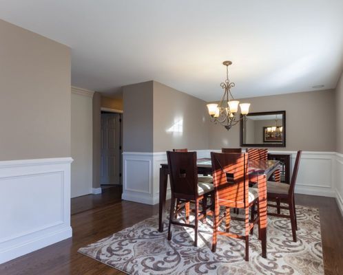 A dining room with a table and chairs and a rug