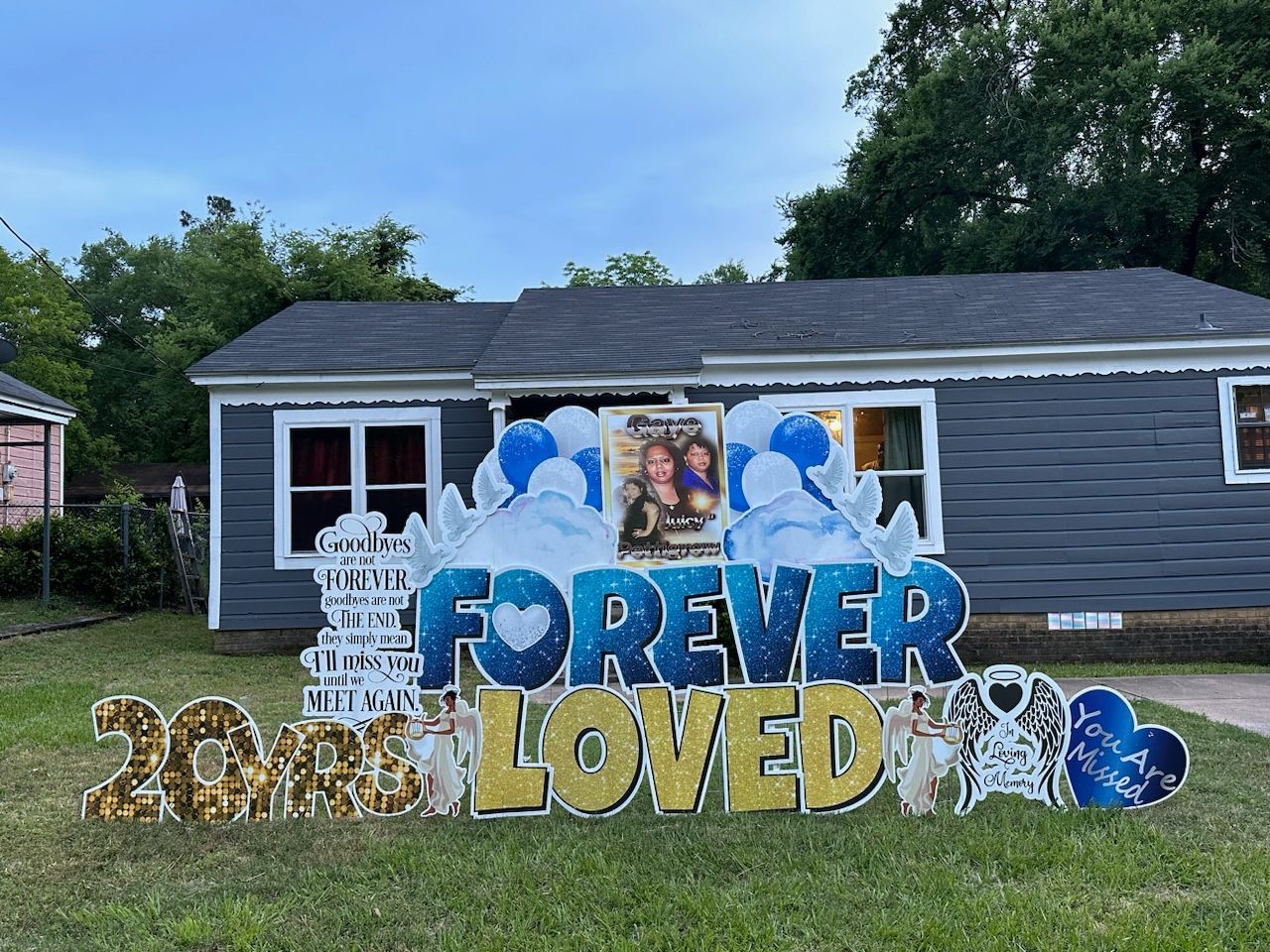 A yard sign that says `` forever loved '' is in front of a house.