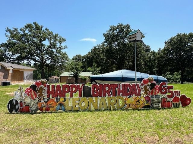 A happy birthday sign for leonardo is in a grassy field.