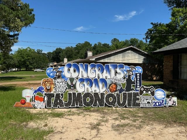 A sign that says congrats grad tajmonque is in front of a house.