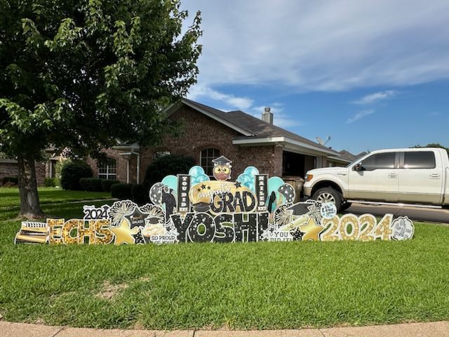 A white truck is parked in front of a house with a graduation sign in front of it.