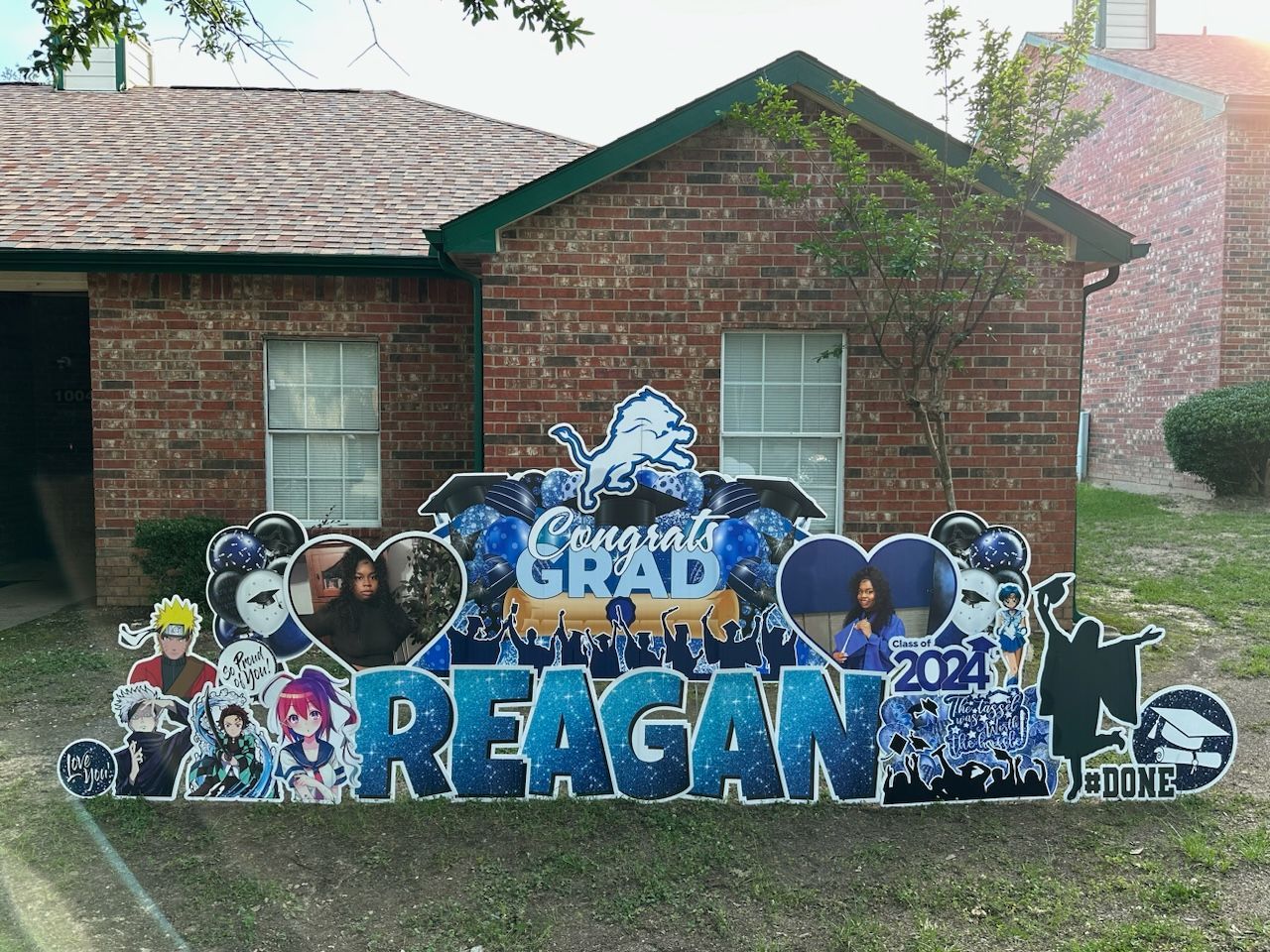A congratulations sign for reagan is in front of a brick house.