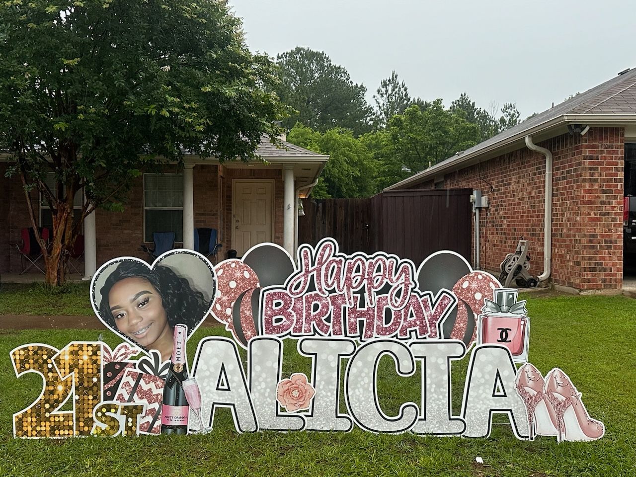A birthday sign for alicia is in front of a brick house.