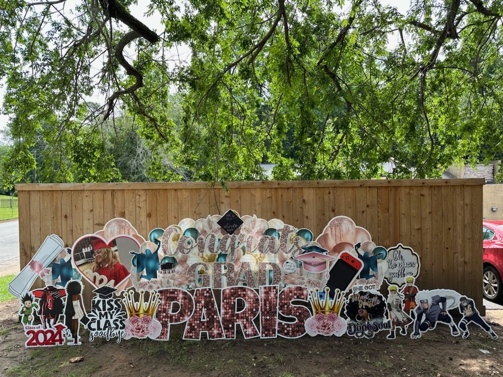 A large sign that says `` paris '' is sitting in front of a wooden fence.