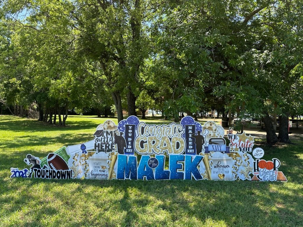 A large sign in the middle of a grassy field with trees in the background.