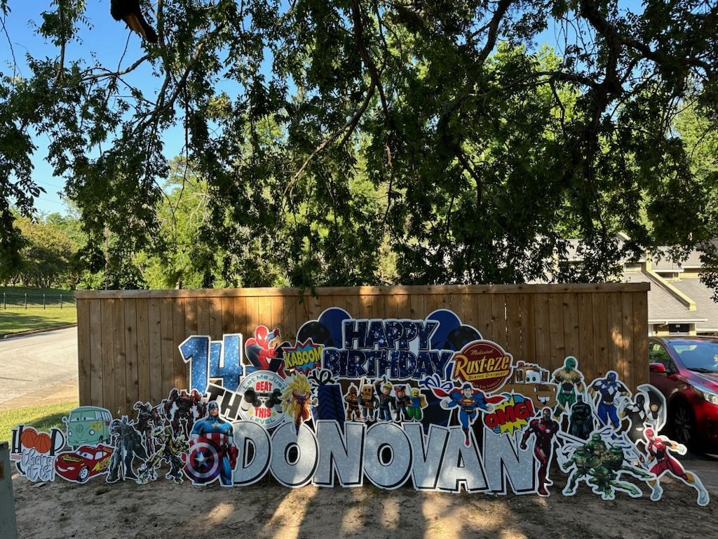 A birthday sign for a boy is sitting in front of a wooden fence.