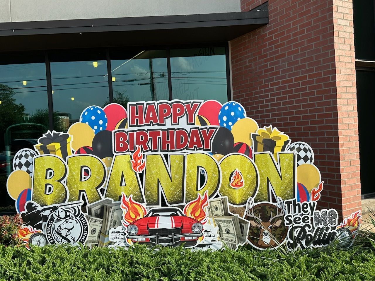 A happy birthday sign for brandon is in front of a brick building.