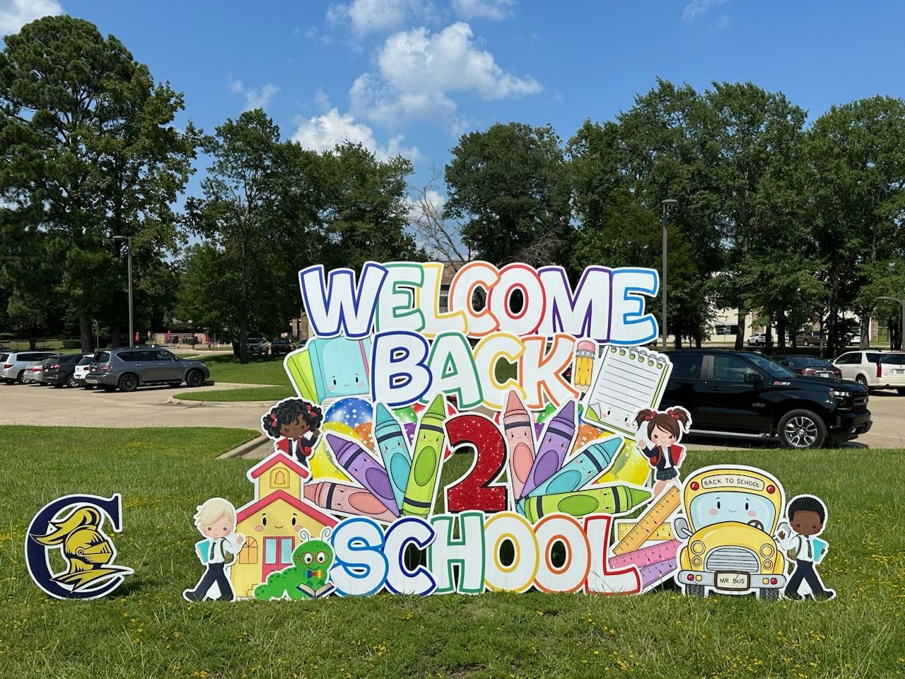 A welcome back to school sign is sitting on top of a lush green field.